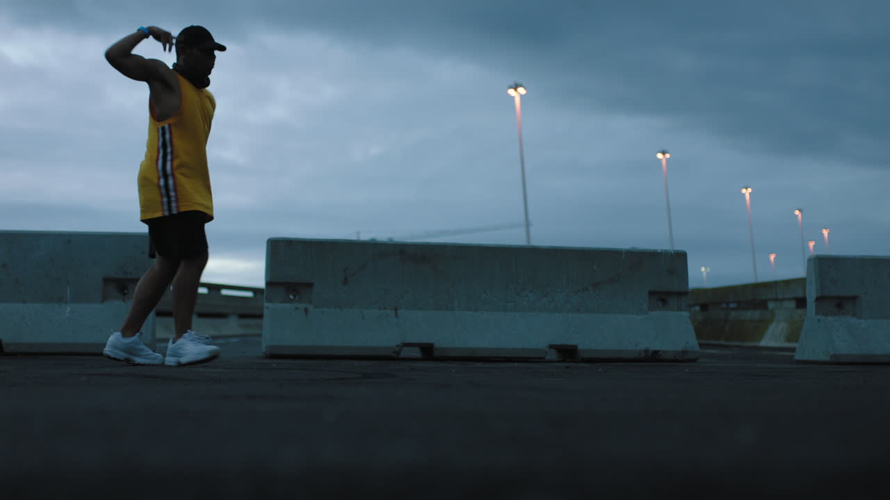 hombre bailando joven bailarín de break realizando movimientos modernos de baile de hip hop practicando coreografía de estilo libre urbano en una ciudad urbana nublada