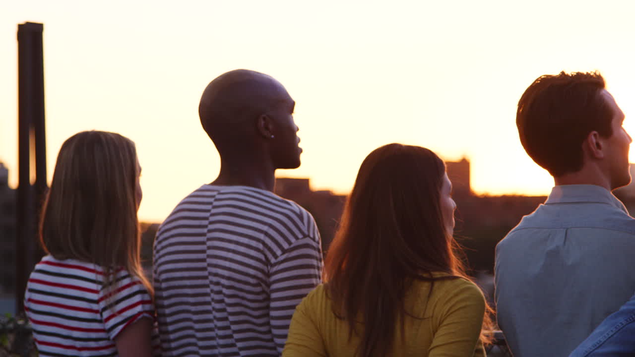 Friends admiring the view from a rooftop at sunset, close up