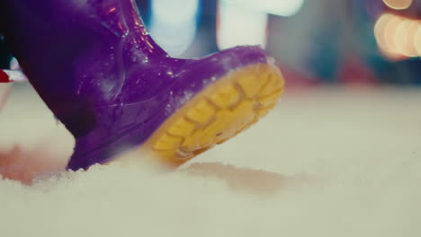 purple and yellow rain rainy boot child playing in ice white snow during winter season