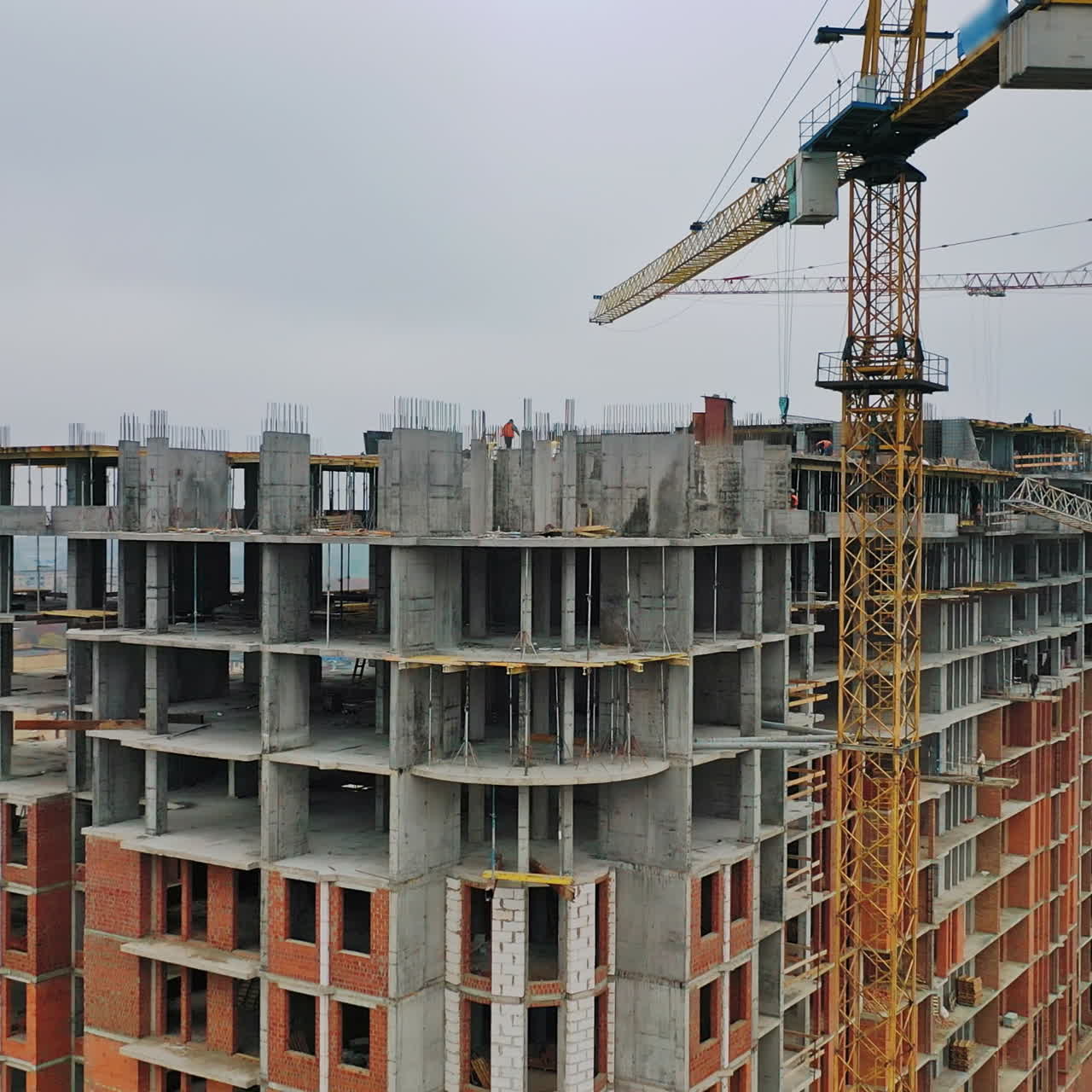New construction site in the city. Two big cranes constructing the urban building. Construction of high-rise building on the city background. Aerial view. Round motion of camera.
