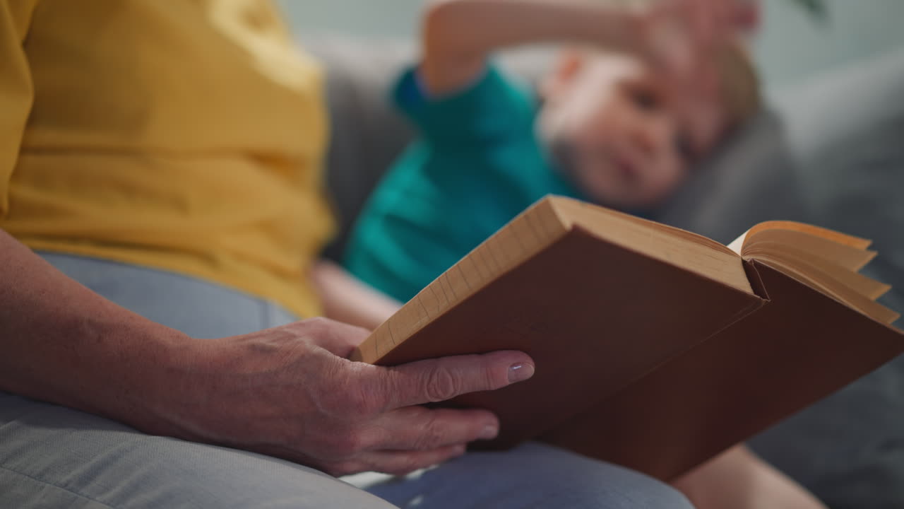 Livro de contos de fadas clássicos lido por uma senhora para um menino pequeno no sofá