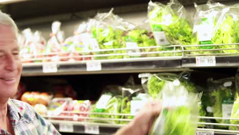 hombre mayor eligiendo ensalada en el supermercado