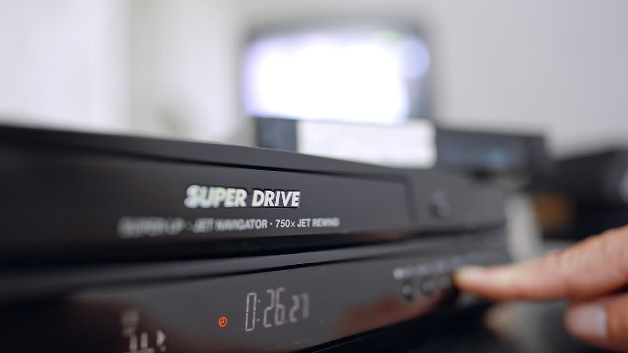 Dito che preme i pulsanti anteriori del videoregistratore. Un dito si avvicina ai pulsanti di controllo di un registratore a nastro vintage in un ambiente domestico