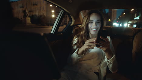 mujer de negocios juguetona riendo en una videollamada en un teléfono inteligente en un coche de negocios.