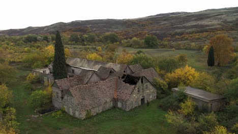 Scenic-View-Ruins-Of-An-Old-Abandoned-House-With-Lush-Foliage-And-Mountain-Ridges-At-Background-In-Asureti,-Georgia