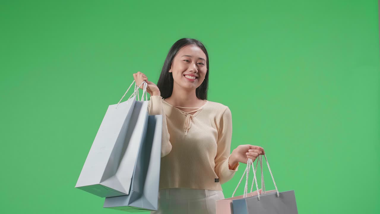 An Asian Shopping Woman With Shopping Bags Smile To Camera While Standing In Front Of Green Screen