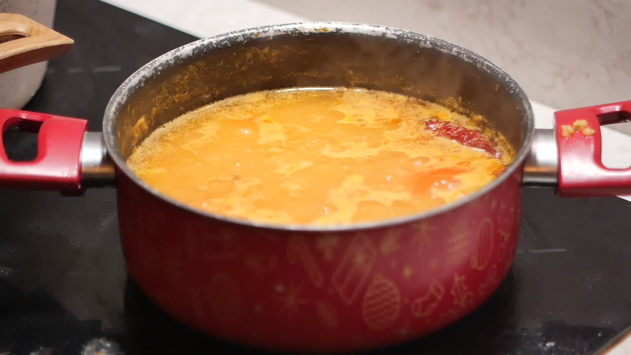 Zuppa arancione che bolle in una pentola rossa su un fornello