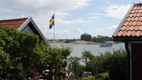 swedish flag at summer cottage with boat in background, sweden