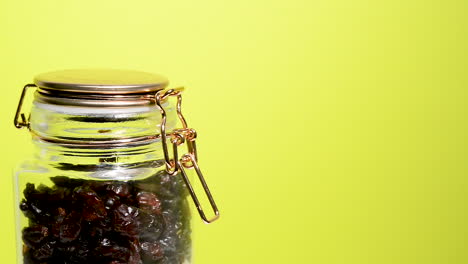 detail of an airtight mason jar rotating with dehydrated cranberry on a neon yellow background