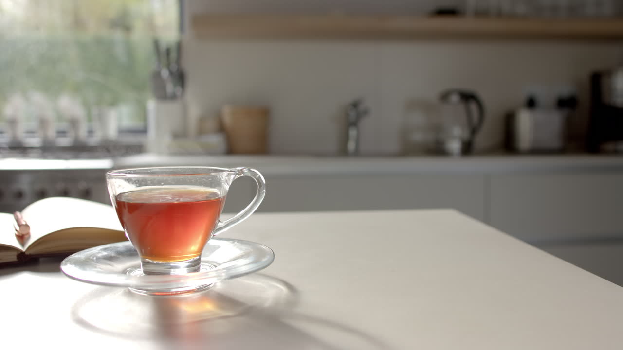 A cup of tea sitting on table with a book partially visible