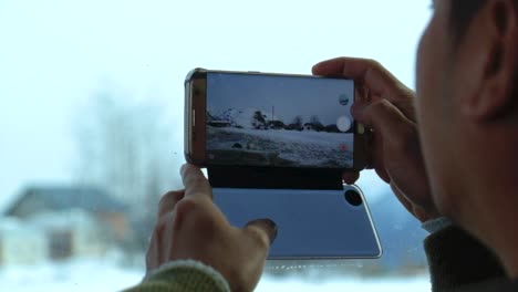 adult male using a galaxy s7 edge to record snow landscape from a moving vehicle