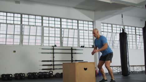 hombre caucásico en forma saltando en la caja de pylo en el gimnasio