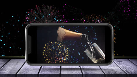 animación de botella de champán y vaso en la pantalla del teléfono inteligente y fuegos artificiales en el fondo