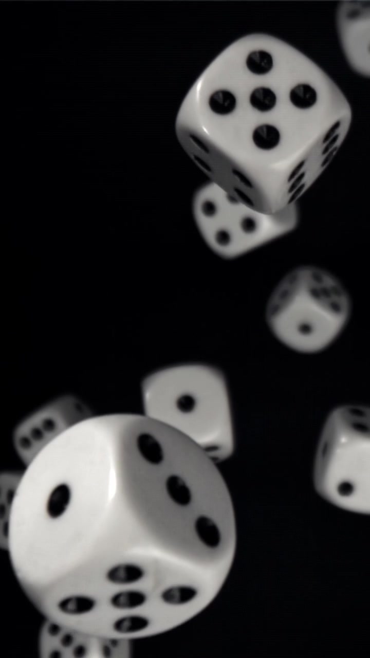 Hvide terninger, der falder i slowmotion mod en sort baggrund.