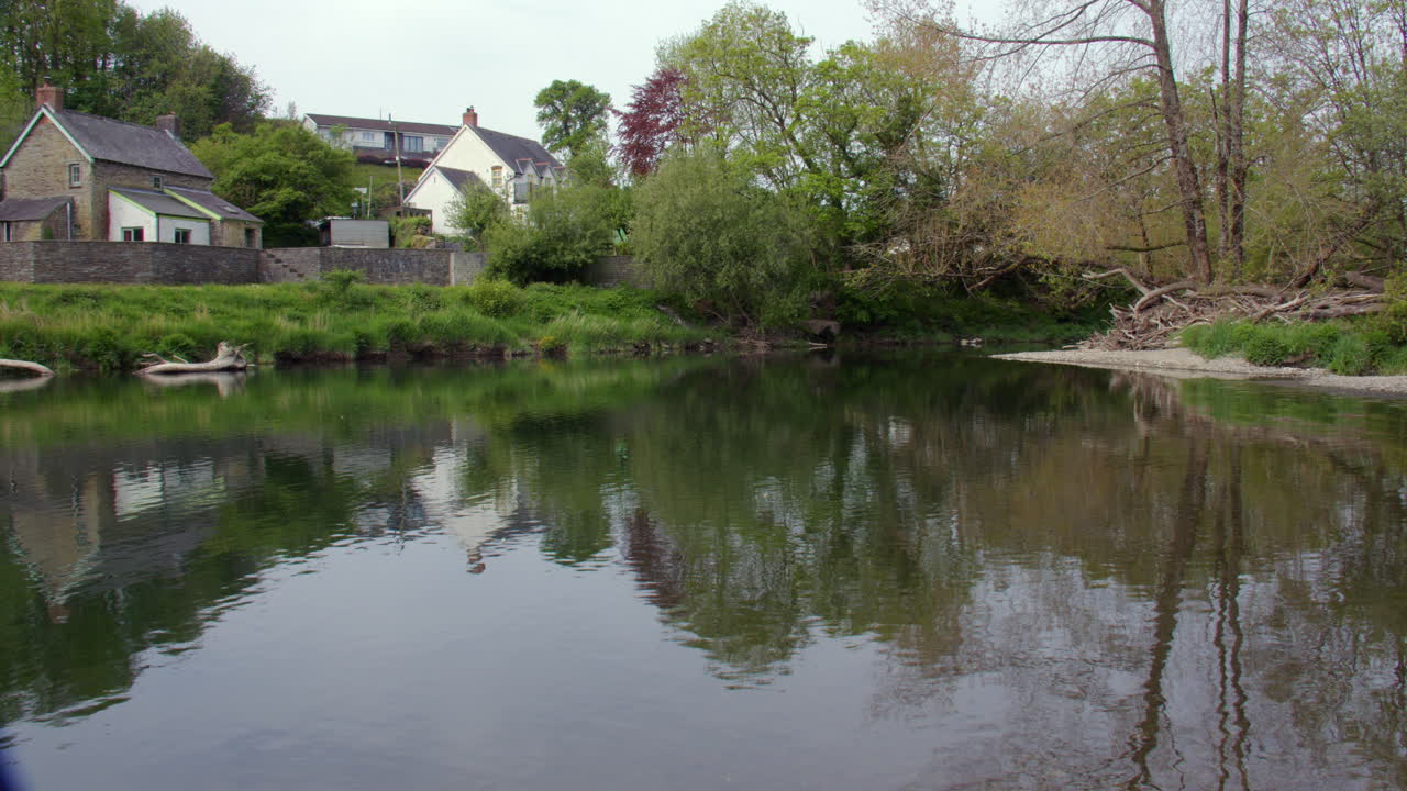 Panning Wide shot of the river Teifi flowing around an island at Cenarth bridge at Cenarth Falls