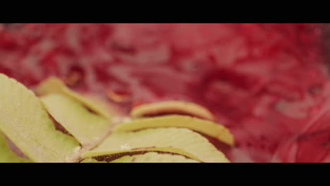 close-up of green leaves in red liquid