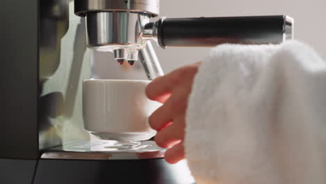 lady brews beverage with coffee machine. young woman picks up cup of coffee from machine. cozy morning scene with careful woman prepared breakfast