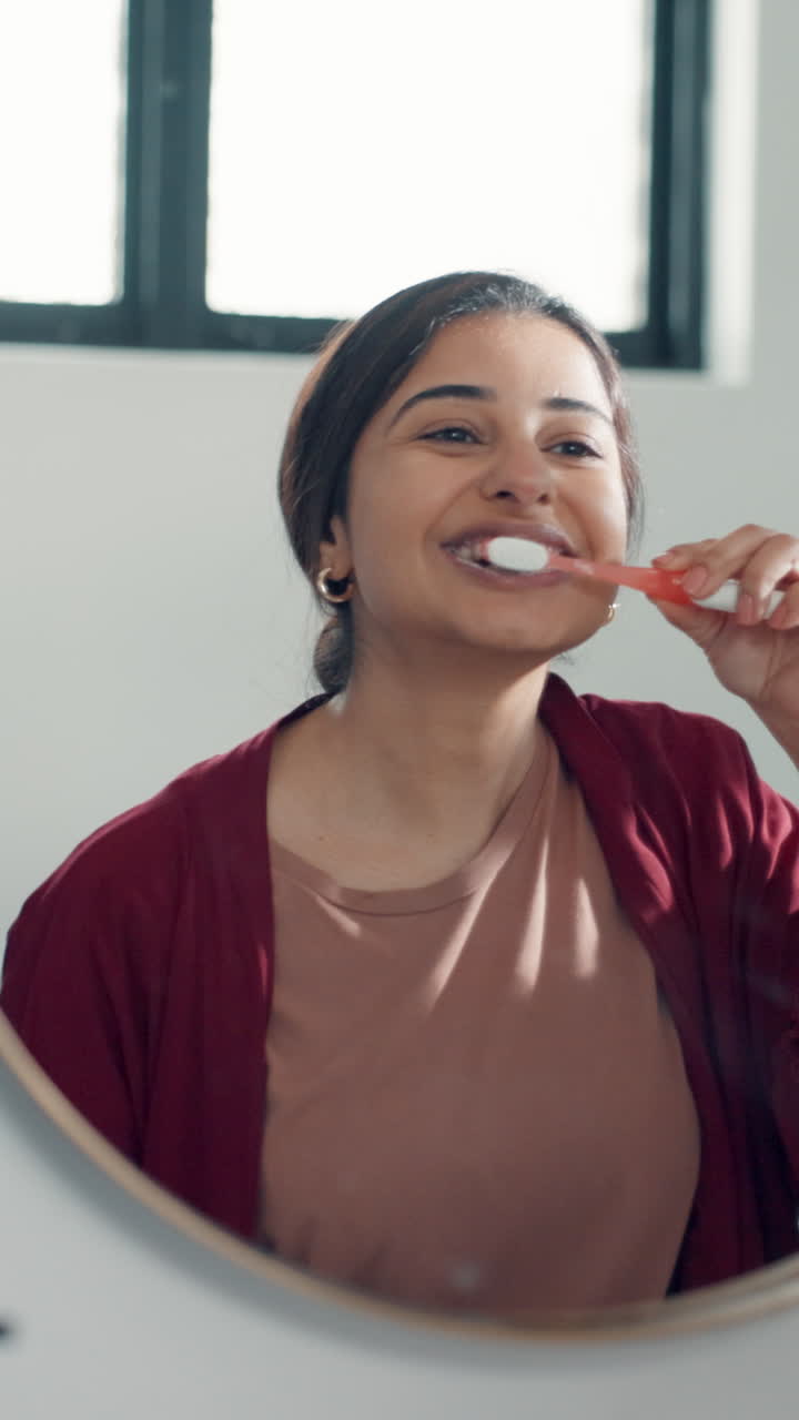 Young Woman Brushing Her Teeth in Bathroom Mirror