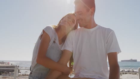 una joven pareja de adultos relajándose junto al mar.