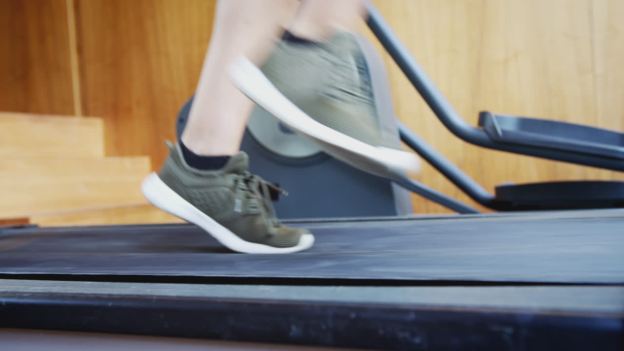 Close Up Of Feet As Man Exercises Running On Treadmill