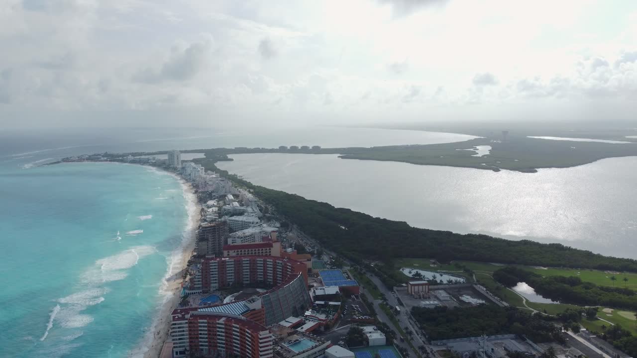 유카탄 반도의 카리브해 연안의 모래, 파도, 나무, 도로 및 건물.