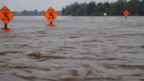 flooded road with flash flood warning signs