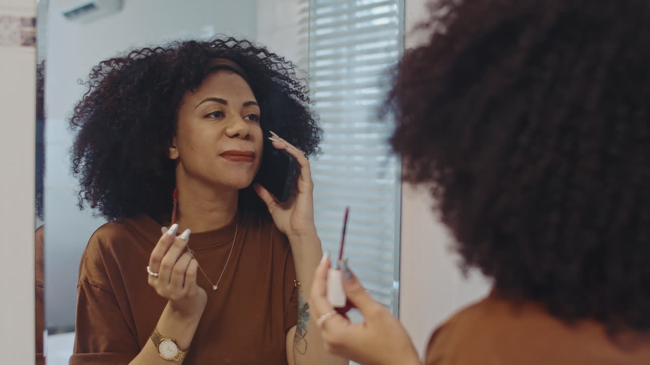 Hispanic Woman Applying Lipstick and Talking on Smartphone