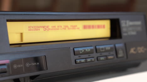 deteniendo y descargando cinta de cassette de video vhs de un reproductor vintage de los años 80, de cerca