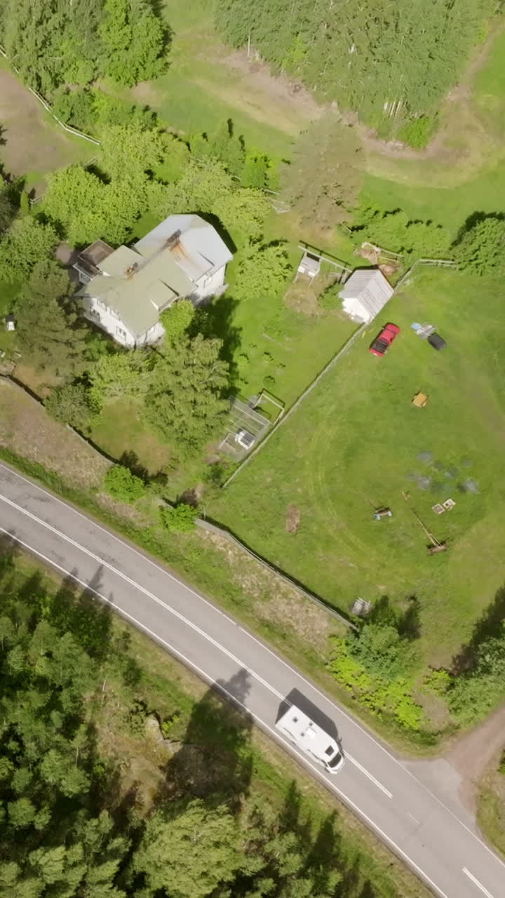 Vertical drone shot passing barns and farmlands, on the countryside of Finland
