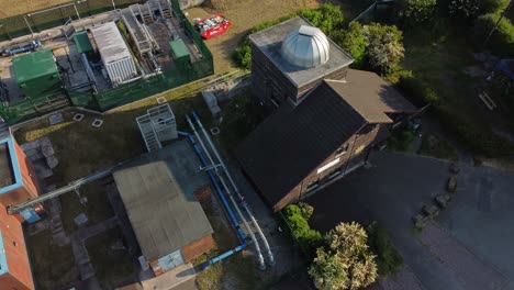 Aerial-view-Pex-hill-Leighton-observatory-silver-dome-rooftop-on-hilltop-farmland-at-sunrise,-descending-orbit