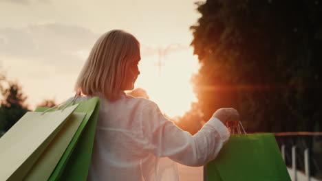 A-shopper-with-packages-walks-down-the-street-at-sunset