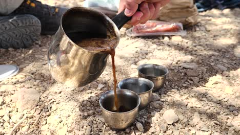 Café-Negro-Recién-Hecho-Que-Se-Vierte-En-Pequeñas-Tazas-De-Metal-Para-Acampar