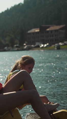 mother and daughter enjoy movement on lake. females look at picturesque scenery sitting in catamaran slow motion. tourists ride on water transport on sunny day side view