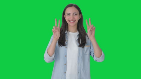 chica india feliz mostrando el signo de la victoria pantalla verde