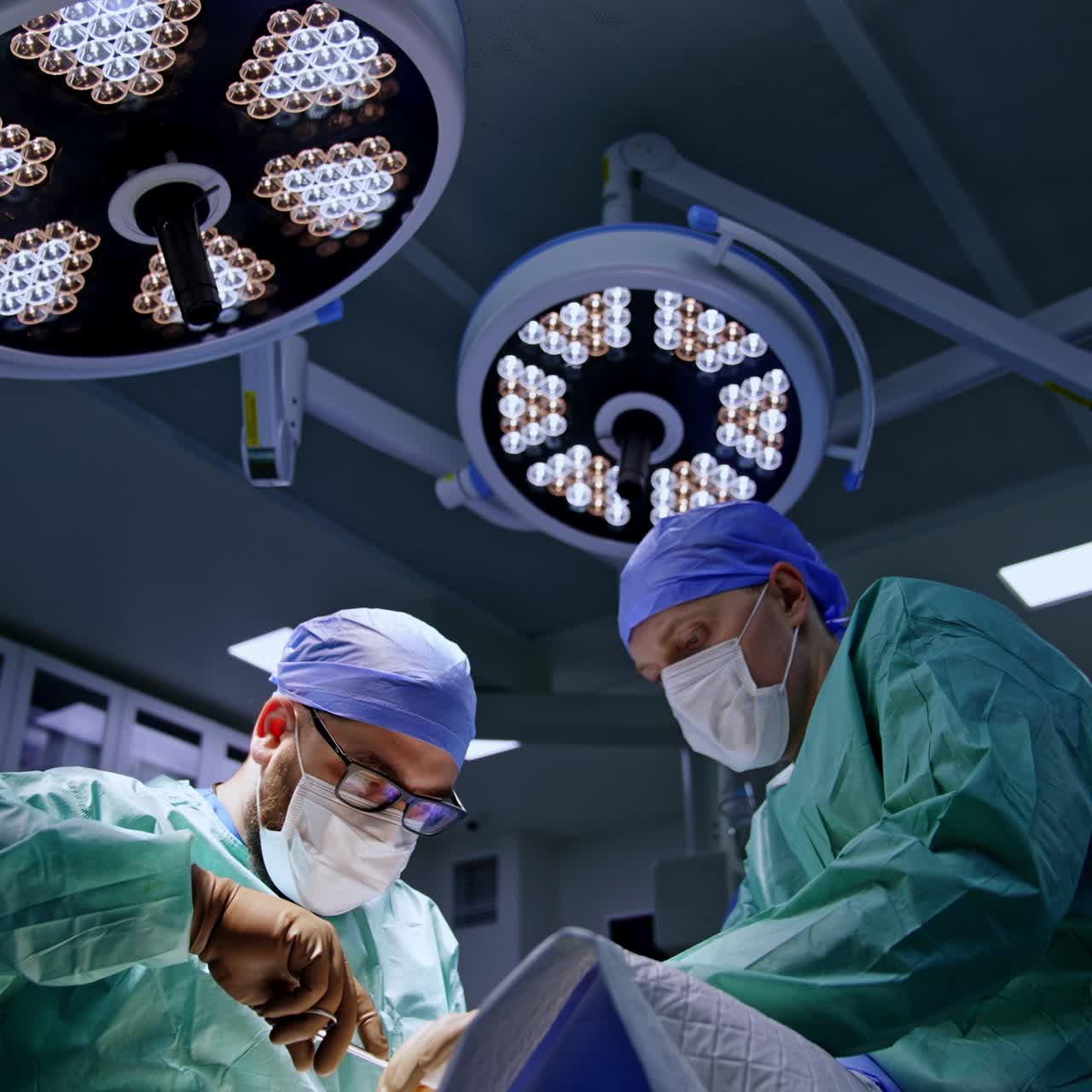 Doctors cooperate at surgical procedure on foot in modern surgery room. Low angle view