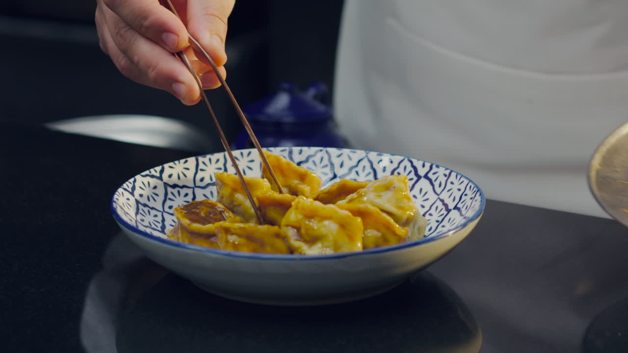 Chef places ravioli and pours sauce onto an elegant plate, highlighting the texture and gourmet presentation