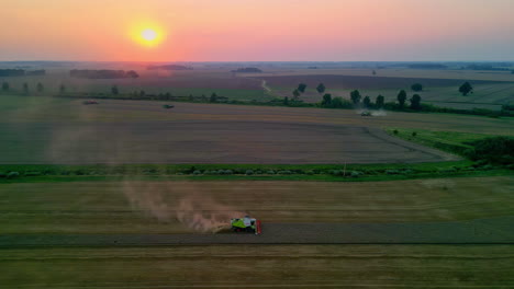 Combine-harvesters-gathering-wheat-crops-in-the-farmland-countryside---aerial-view-at-sunset