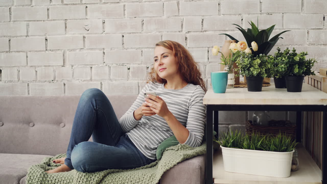 Donna che si rilassa su un divano usando uno smartphone