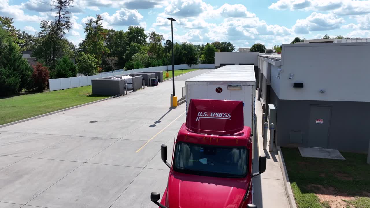 Walmart Truck parking backwards at ramp of warehouse in American town. Aerial orbit shot. Loading of goods for delivery on sunny summer day.
