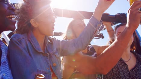 Group-of-friends-toasting-beer-bottles-in-the-beach-4k