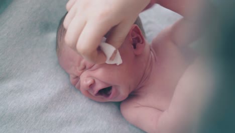 boy-lies-on-table-and-mother-hand-rubs-eyes-with-cotton-pad