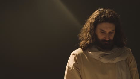 retrato de un hombre vestido con túnicas con cabello largo y barba que representa la figura de jesucristo de pie piscina de luz