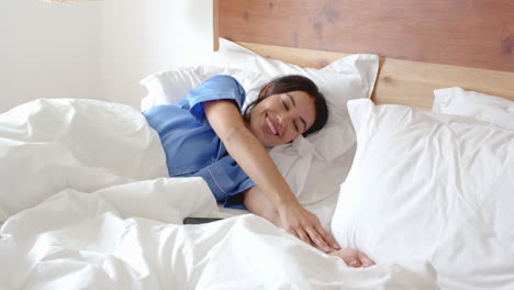 woman waking up in bed, stretching and smiling, enjoying morning relaxation, at home