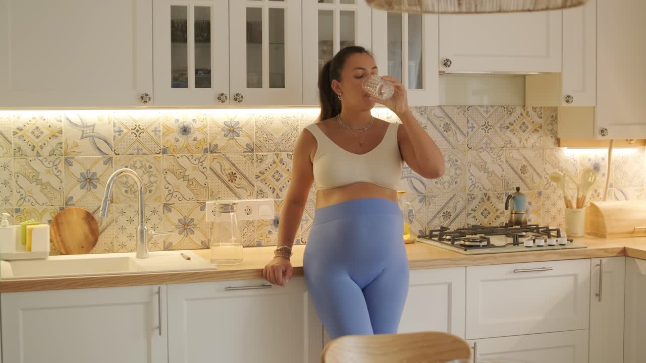 Una donna incinta che si gode la sua routine quotidiana a casa, rilassandosi in salotto e mangiando in cucina. La scena evidenzia comfort, maternità e momenti di cura di sé in un ambiente accogliente