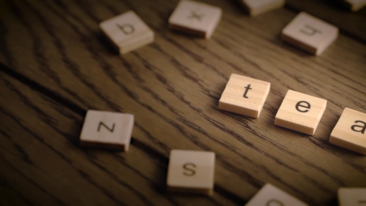 Wooden tiles spell the word tea as the camera pans slowly across a rustic wood surface in warm lighting.