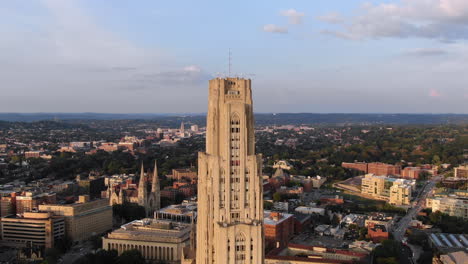 a "zolly" aerial establishing shot of the top of the cathedral of learning in pittsburgh's oakland district on an early summer evening