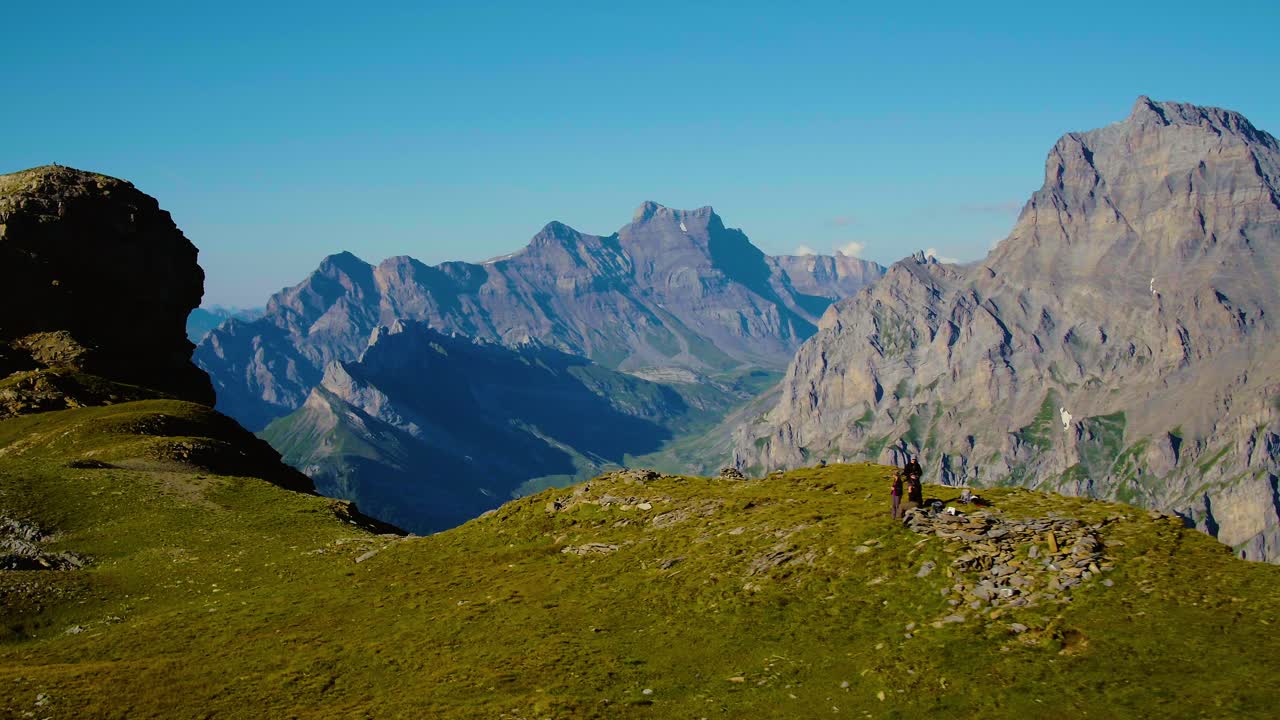 sobrevolando excursionistas en el paso de montaña con altos picos rocosos en el fondo col des perris-blancs - los alpes, suiza