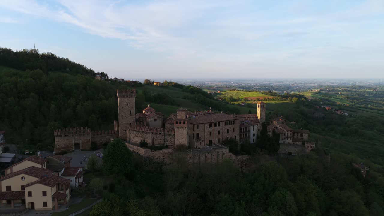 Aerial drone revealing medieval Vigoleno castle and fortified village perched on rolling hills at golden hour sunset, Emilia-Romagna, Italy. [5, 21, 47]