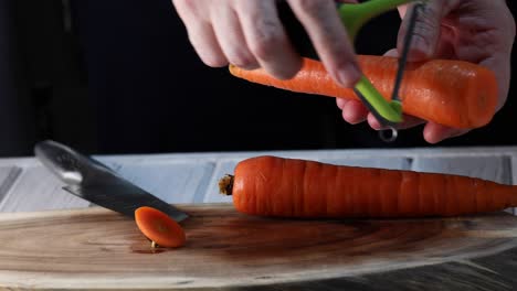 a man peels a carrot on a wooden background. 4k video