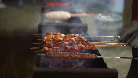 skewers of meat grilling on a barbecue with smoke rising